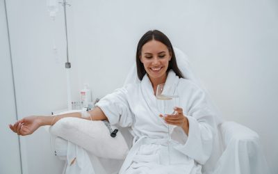 Woman in white bathrobe drink water during medical procedure in beauty clinic. High quality photo